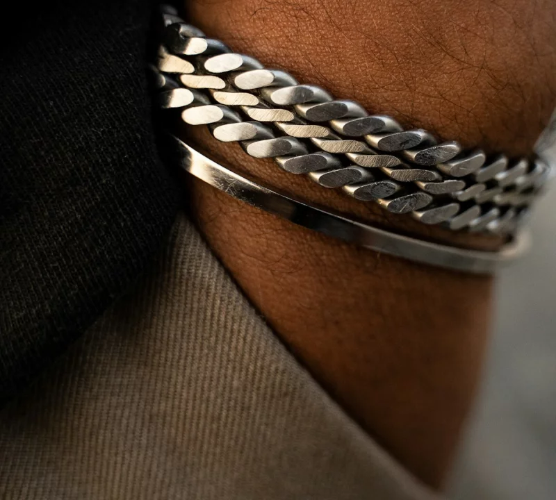Zilveren schakelarmbanden om een herenpols