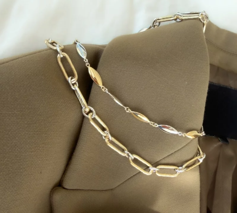 Gouden schakelcollier op een beige trui