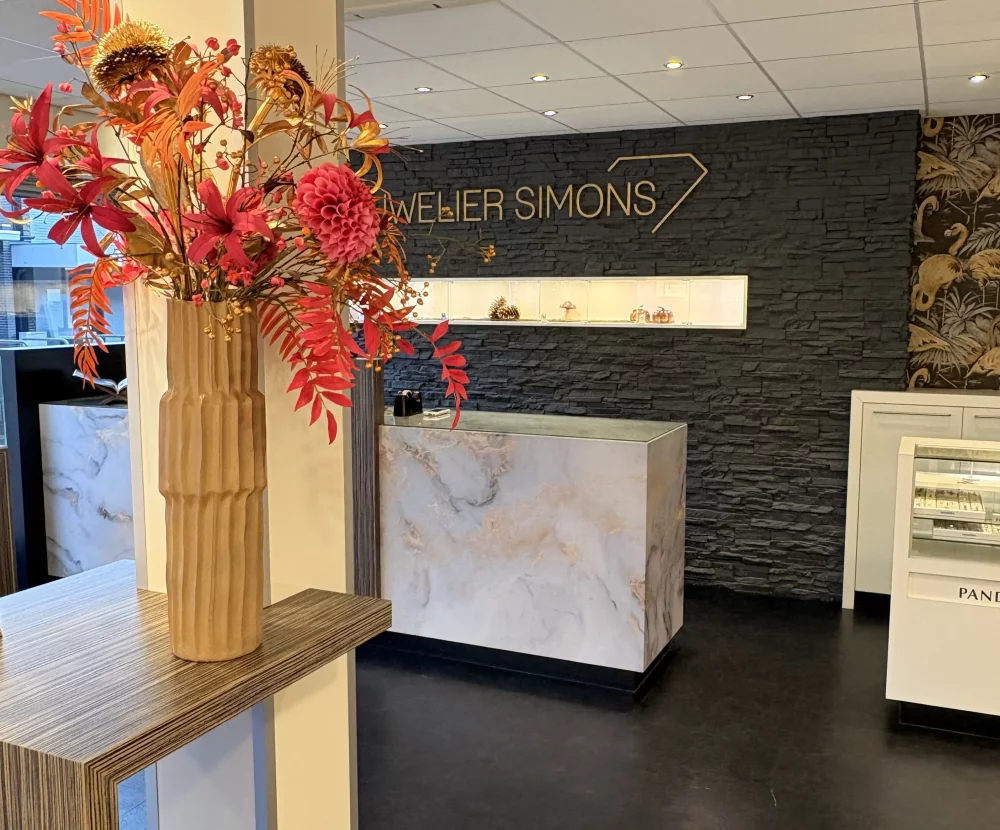 De toonbank en vitrines van Juwelier Simons, met herfstbloemen